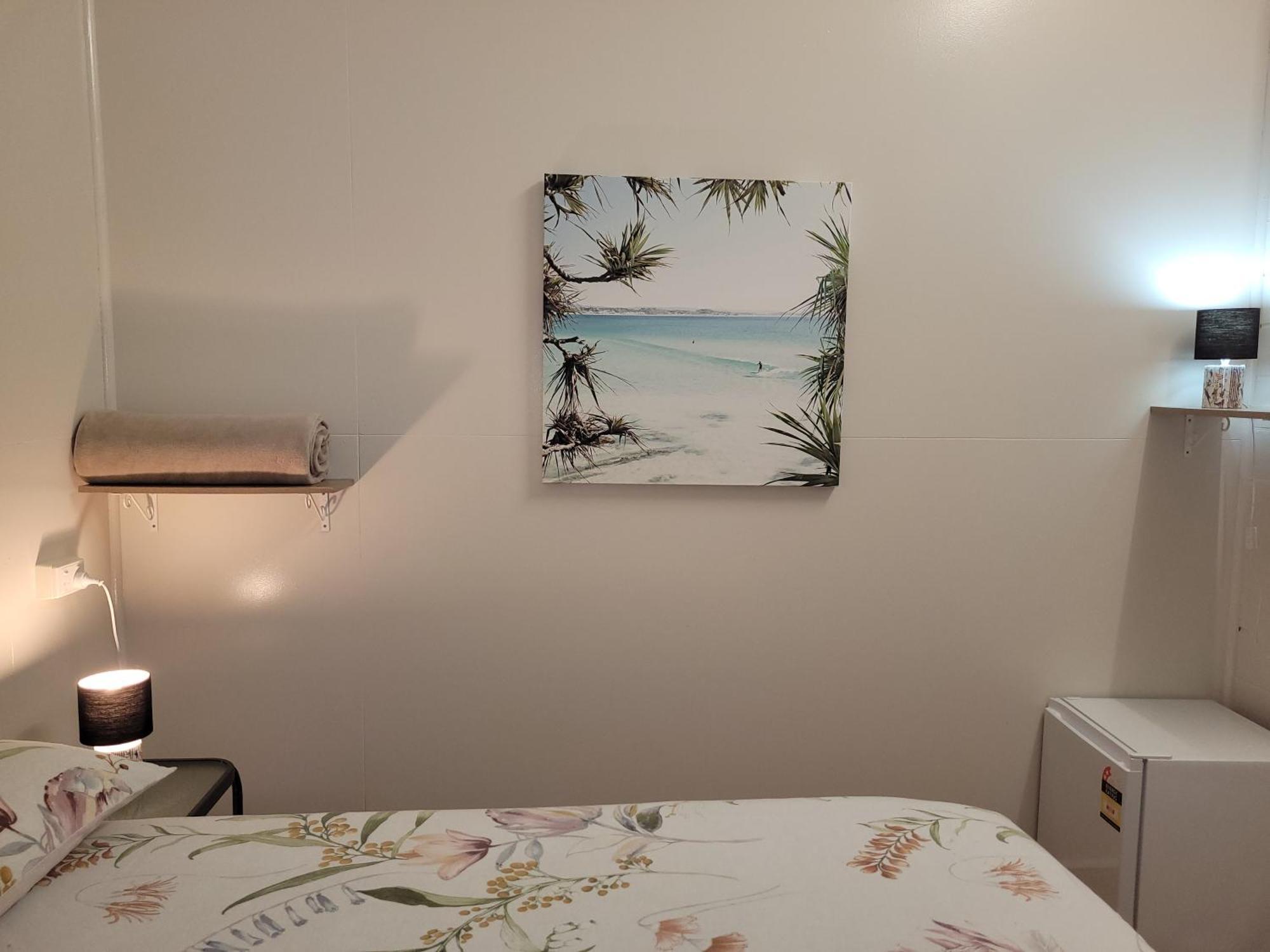Travellers Paradise Cairns Luaran gambar A photograph of a bedroom with a bed, a nightstand, a lamp, a painting, and a television